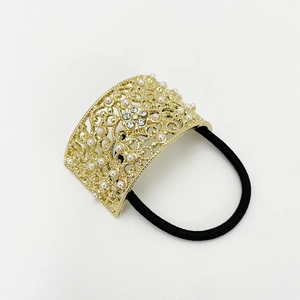 Detail of gold metal hollow hair tie with inlaid pearls and rhinestones on white background
