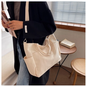Detailed view of cream canvas tote bag side pocket and adjustable shoulder strap