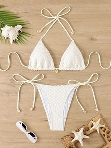 Close-up of textured fabric and sea shell charms on the tie-side bikini bottom