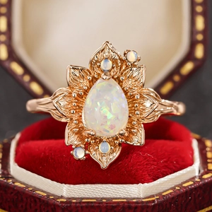 Dettaglio macro dell'anello con opale a goccia e montatura floreale in scatola rossa
