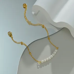 Detail of elegant gold double-chain bracelet featuring white pearls and beads on mirror