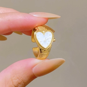 Detail of golden heart-shaped ring watch with polished metal chain and white dial