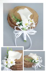 Close-up of white calla lily boutonniere with small flower clusters and a ribbon bow