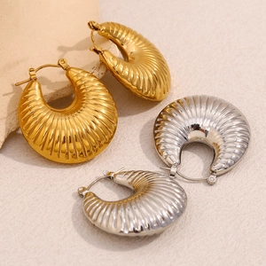 Thick twisted croissant hoop earrings in gold and silver finish on stone display