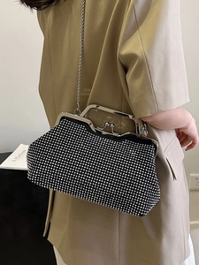 Elegant black shell bag with silver rhinestones and metal handle on khaki suit