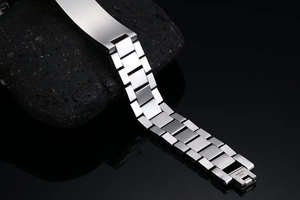 Detail of silver stainless steel bracelet with engraved folding clasp on black rock