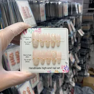 Handgemaakte nude roze plaknagels met witte 3D-kunst en elegante parelaccenten