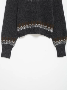 Detail of grey jacquard knit sweater featuring brown geometric patterns and ribbed cuffs