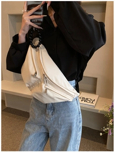 Close-up of white leather crossbody chest bag featuring multiple zippers and beaded strap