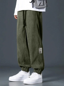 Detailed view of dark green corduroy joggers with drawstring waist and logo patch