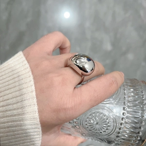 Polished silver brass water drop open ring on finger with embossed glass and marble background