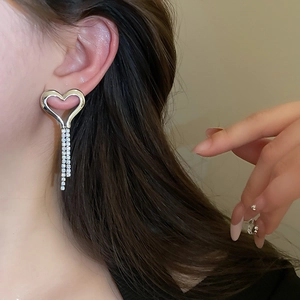 Close-up of heart tassel earrings with silver finish and sparkling rhinestones on a model