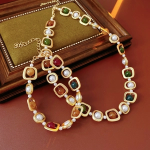 Gros plan d'un collier vintage doré avec pierres colorées et perles en boîte velours