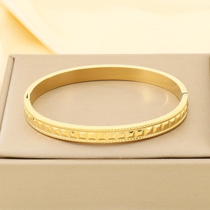 Macro view of gold geometric knurled texture on the stainless steel hinged bangle