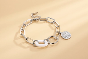Détail de bracelet chaîne argentée avec maillon acrylique blanc et pendentif rond