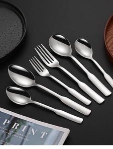 Elegant setting of four stainless steel spoons and forks on a dark modern background