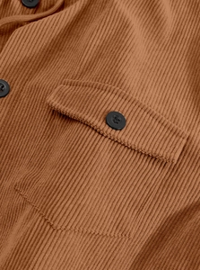 Close-up of brown corduroy jacket fabric texture with flap pocket and black button