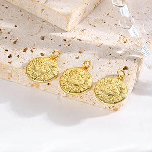Detailed view of three golden sun-face pendants on a minimalist beige stone background