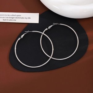 Macro shot of large silver hoop earrings on black leather with a minimalist metal finish