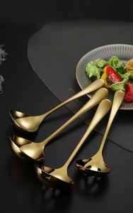 Polished gold 304 stainless steel soup ladle and slotted spoon set on a black dining mat