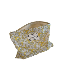 Floral cotton makeup bag in yellow with white flower patterns and zipper closure