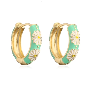 Close-up of gold-plated huggie earrings with mint green enamel and daisy patterns