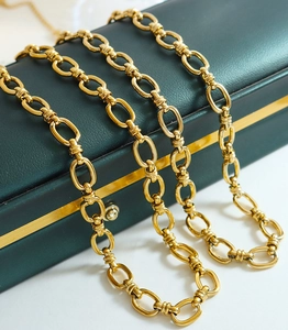 Detail of a gold interlocking chunky oval link chain necklace on a green leather gift box