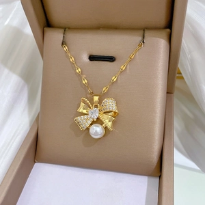 Macro shot of gold bow necklace with heart gemstone and pearl detail in jewelry box