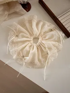 Close-up of cream lace hair scrunchie with delicate bow details and vintage metal beads