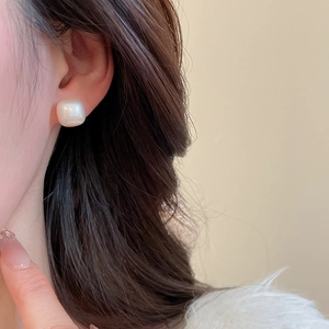 Close-up of elegant square pearl stud earring with soft satin luster worn by a model