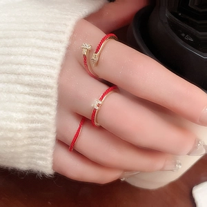 Close-up of gold three-piece ring set with H logo, red enamel, and nail design