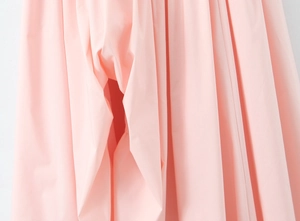Detail showing the pink fabric texture and side slit of the stylish halter dress