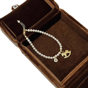 Elegant pearl bracelet with golden horse and coin charms in a velvet jewelry box