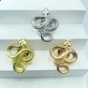 Detailed view of snake brooches in gold and silver with textured scale patterns