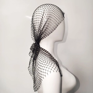 Dettaglio del copricapo a rete nero con paillettes scintillanti su un manichino da esposizione
