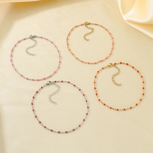 Set of four colorful resin bead stainless steel anklets on a beige silk fabric