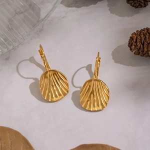 Golden leaf texture shell earrings in stainless steel on marble surface with pine cones