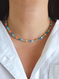 Close-up of multicolor glacier blue cat eye beaded necklace worn on a woman's neck