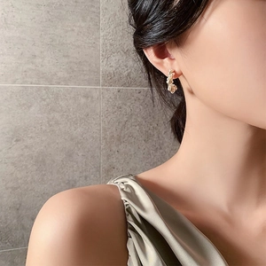Close-up of elegant C-shaped pearl earrings with cubic zirconia on a female model