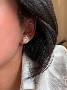 Primo piano dell'orecchino a perno con perla iridescente e base in metallo argento