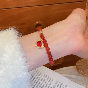 Gros plan d'un bracelet en perles d'agate rouge avec un pendentif cheval à bascule