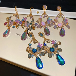 Close-up of elegant flower tassel earrings with aurora crystal teardrops and gold chains