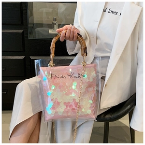 Detail of transparent PVC handbag featuring bamboo handle and pink sequin interior pouch