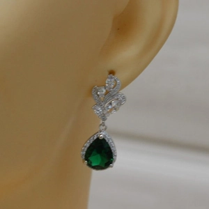 Close-up of elegant pear-shaped green zircon drop earrings worn on a model's ear