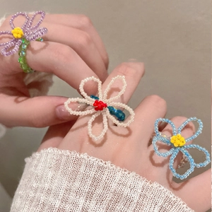 Détail de bagues fleurs en perles de cristal faites main en violet, blanc et bleu