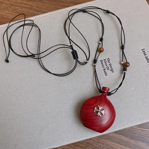 Close-up of a vintage resin pendant necklace with wood texture and silver cross inlay