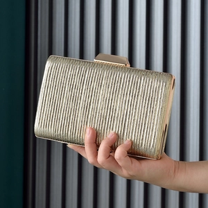 Golden pleated evening clutch bag with metallic vertical stripes and top clasp closure