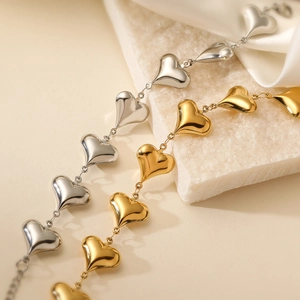 Minimalist 18K gold and silver plated heart bracelets displayed on elegant stone and silk