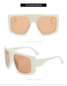 Close-up of beige oversized flat top sunglasses with orange lenses and polished frames