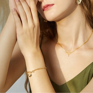 Detail shot of a double-layered gold necklace with zircon and heart charm bracelet set